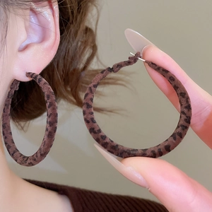 Gros plan sur des boucles d'oreilles rondes à motif léopard avec texture velours