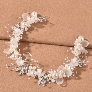 Dettaglio dell'accessorio per capelli da sposa con perle e foglie argentate su tessuto