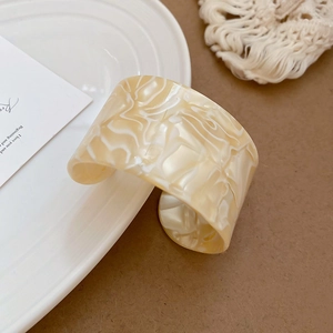 Macro shot of wide acrylic cuff bracelet with cream marble texture in elegant set