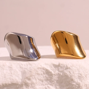 Detail of chunky gold and silver irregular geometric rings on white stone surface