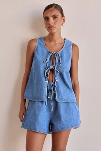 Detalle de conjunto denim azul con top sin mangas de cordones y pantalones de talle alto