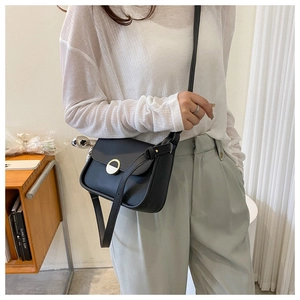 Chic black underarm bag with metal buckle shown as a crossbody on a stylish model