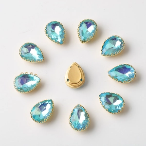 Macro detail of teardrop blue rhinestones in gold claw settings for DIY sewing