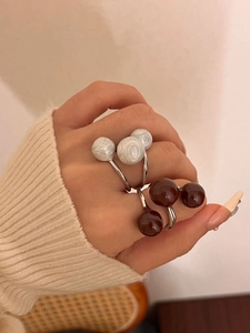 Detailed view of layered silver open rings with white marble and brown glossy beads