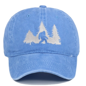 Macro detail of Sasquatch embroidery and pine trees on a blue washed cotton baseball cap