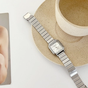 Minimalist silver square quartz watch with metal chain strap on ceramic plate