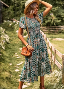 Détail de robe midi fleurie verte bohème avec buste smocké et jupe à volants étagés
