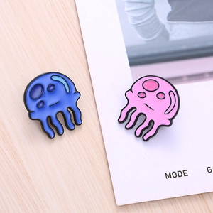 Cute blue and pink jellyfish enamel pins set on a minimalist wood and white background