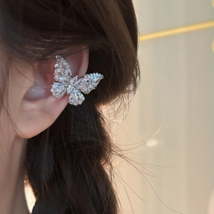 Detailed close-up of a silver butterfly ear cuff with zircon crystals on a real ear