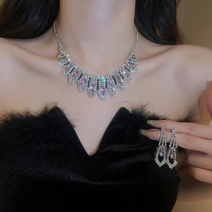 Close-up of sparkling tassel necklace and earring set with purple and white crystals