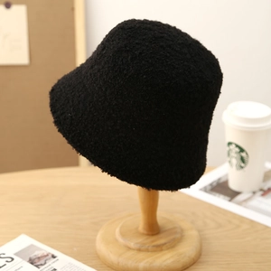 Close-up of black fleece bucket hat with plush texture on a wooden stand for winter style