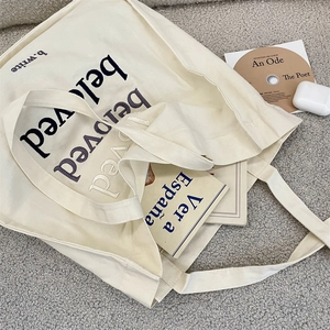Detail of beloved letter embroidery on off-white canvas tote bag for students