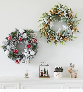 Detail of Christmas wreath with pine cones and berries hung over a white fireplace