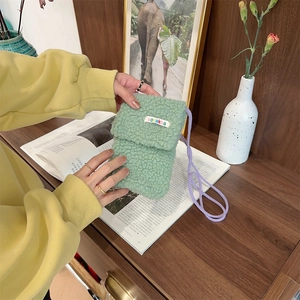Detail of light green plush faux shearling phone bag with purple knotted rope strap