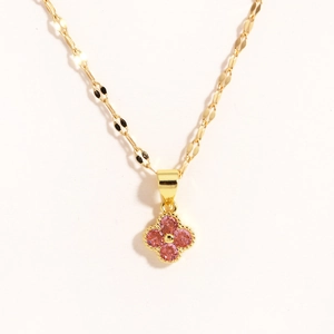 Dettaglio collana a quadrifoglio dorata con gemme rosa e catena a maglia piatta testurizzata