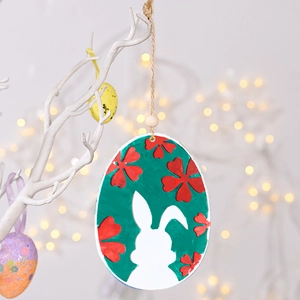 Close-up of Easter egg hanging ornament with white rabbit silhouette and red flowers