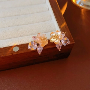 Close-up of floral cubic zirconia earrings with pink petals and gold-plated details