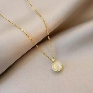 Rotating cat-eye opal pendant necklace with zircon halo on soft beige fabric