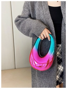 Detail of blue pink gradient circular handbag with mirror gloss finish held by a model