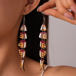 Detail of fish-shaped wood earrings with vibrant printed patterns on a model's ear