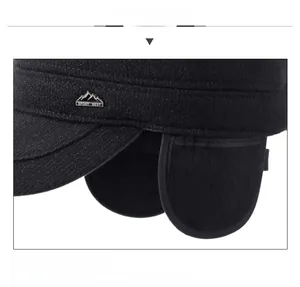 Detail view of winter ear flap hat featuring a metal Sport Best badge on black fabric