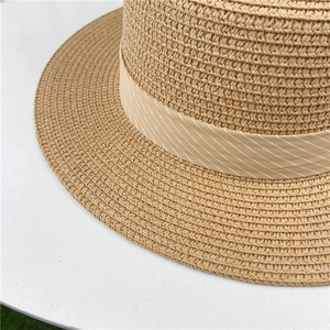 Close-up of finely woven straw hat texture with beige striped ribbon decoration