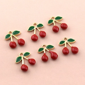 Lot de six breloques cerises avec bordure dorée et feuilles vertes sur fond rose