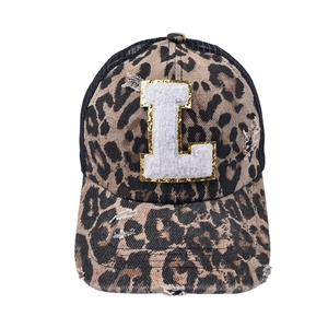 Detailed view of leopard print baseball cap with distressed brim and sequined letter L patch