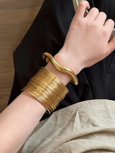 Detail of chunky gold irregular wavy cuff and multi-strand wire wrap wide arm bracelet set