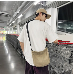 Khaki casual crossbody dumpling bag with wide black strap shown in street style scene