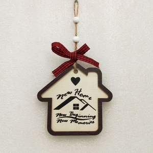 Detail of wooden house ornament with New Home text and red black plaid bow