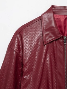 Detail of burgundy woven leather bomber jacket showing collar, zipper, and texture