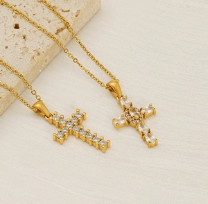 Detailed close-up of golden cross necklaces with sparkling zircon inlay on stone surface