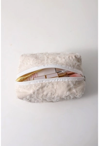 Detail view of beige corduroy cosmetic bag with lace embroidery and zipper closure