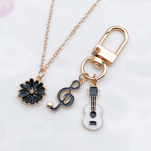Detailed view of gold alloy necklaces with black daisy and music note enamel charms