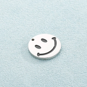 Macro shot of silver smiley face pendant in polished steel on a blue leather surface