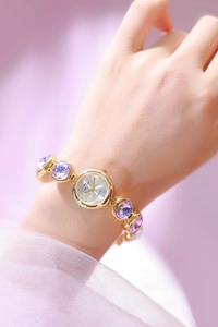 Détails de montre dorée avec bracelet en cristal violet et cadran à quartz blanc