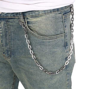 Detail of silver skull buckle square chain accessory worn on denim jeans in punk style