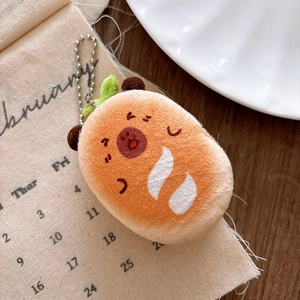 Close-up of cute plush orange character charm with metal bead chain on soft background
