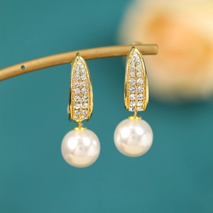 Close-up of pearl drop earrings with sparkling rhinestones on elegant gold metal