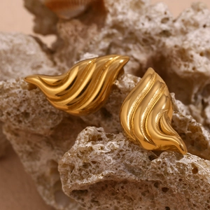 Macro shot of gold-plated stainless steel teardrop earrings on a natural coral rock