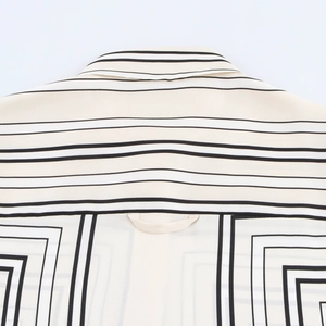 Detail of the collar and back on a beige satin blouse featuring black geometric stripes