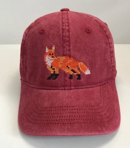 Close-up of pixelated fox embroidery on washed red cotton baseball cap detail