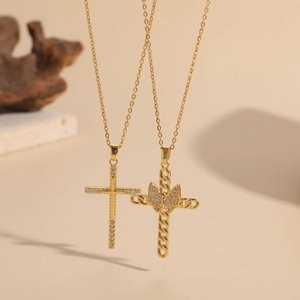 Gold plated zircon cross and butterfly pendant necklaces displayed on natural props