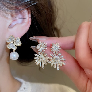 Detailed view of elegant gold floral earrings with white pearls and sparkling zircons