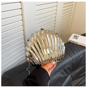 Handheld view of silver shell-shaped evening clutch bag with metallic finish and chain strap