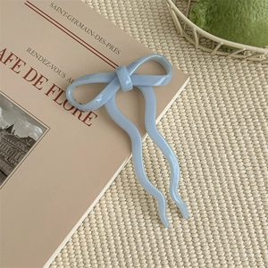 Close-up of a blue bow hair pin on a woven mat next to a French lifestyle book