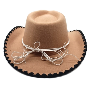 Detail of camel western hat with black stitch brim and white cord band on white background