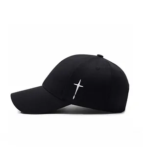 Close-up of a black cotton baseball cap featuring a white embroidered side cross design