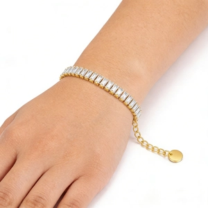 Detail of gold-plated tennis bracelet featuring rectangular cubic zirconia stones on wrist